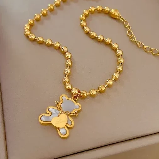 Un bracelet plaqué or acier inoxydable perlé pendentif ours blanc dans un coffret cadeau, avec un pendentif ours.