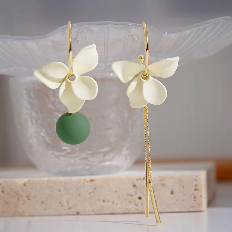 Une paire de boucles d'oreilles avec des fleurs vertes et blanches.