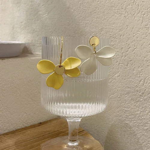 Un verre avec une paire de Boucles d'oreilles asymétriques Pétales de Fleurs.