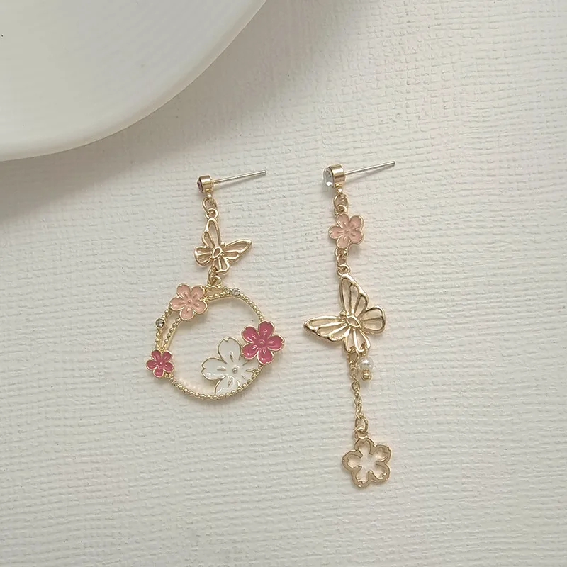 Une paire de boucles d'oreilles avec des fleurs roses et des papillons.