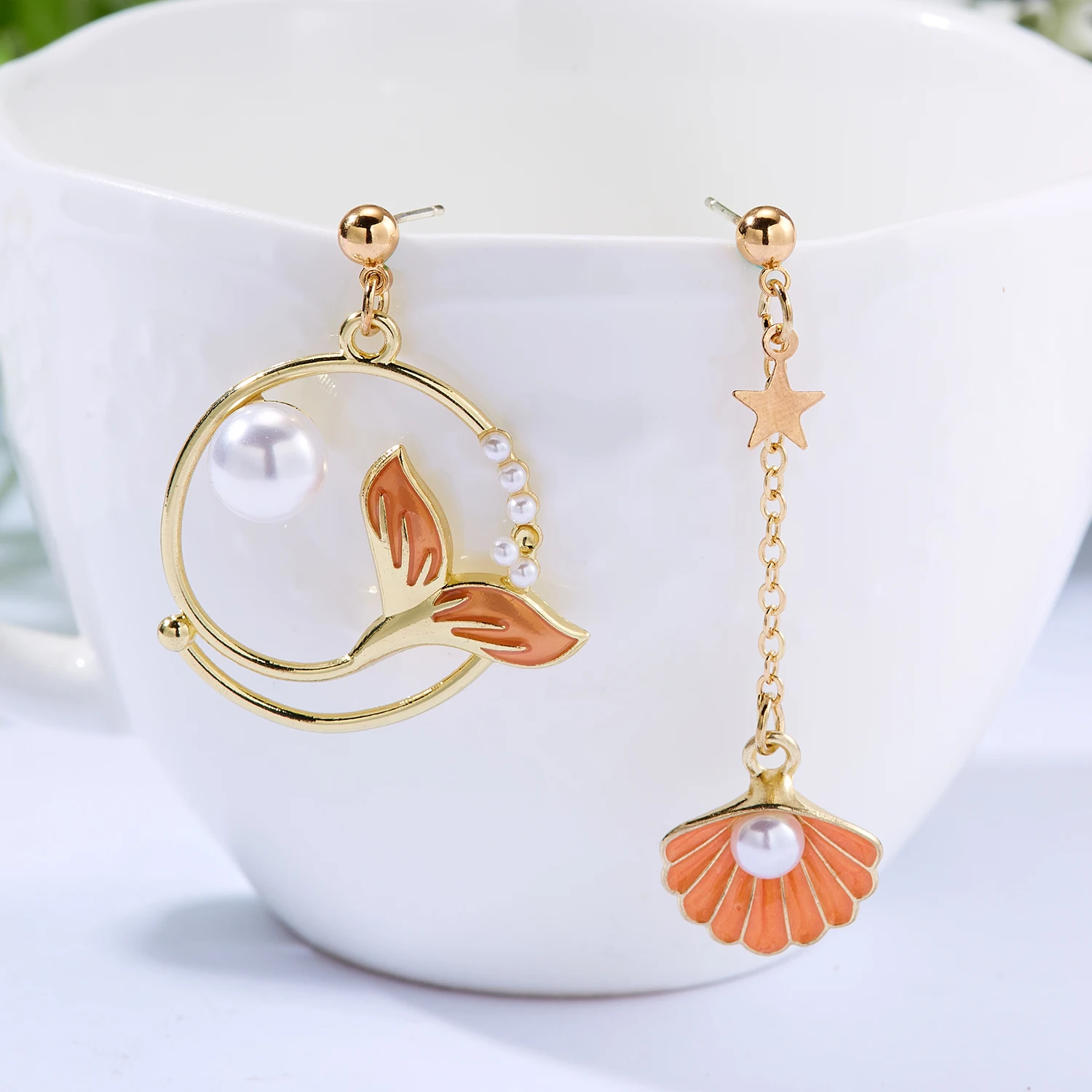 Une paire de boucles d'oreilles avec une sirène et une perle.