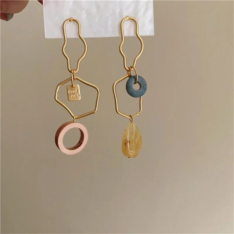 Une paire de Boucle d'Oreille Dépareillée Doré Abstrait rose et bleue avec un design dépareillée.