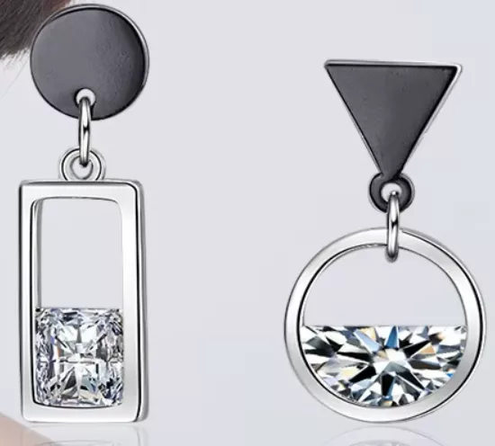 La boucle d'oreille pendante asymétrique rond rectangle associe un rond et un rectangle tenant une pierre précieuse carrée sur une boucle d'oreille, tandis que l'autre combine un triangle et un cercle avec une pierre précieuse ronde à moitié exposée.