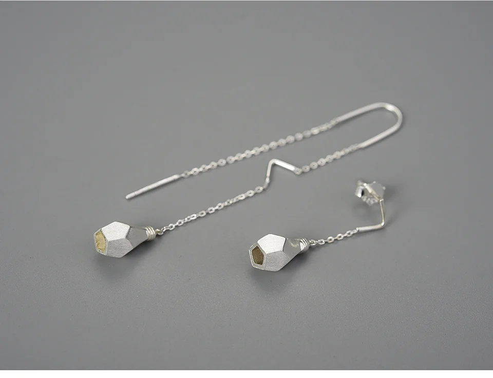 Une paire de boucles d'oreilles asymétriques en argent ROSY Boucles d'oreilles avec pendentifs hexagonaux géométriques, élégamment présentées sur un fond gris uni.